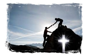 A mountain cross made of stone, with a backdrop of snow-capped mountains and a clear blue sky.